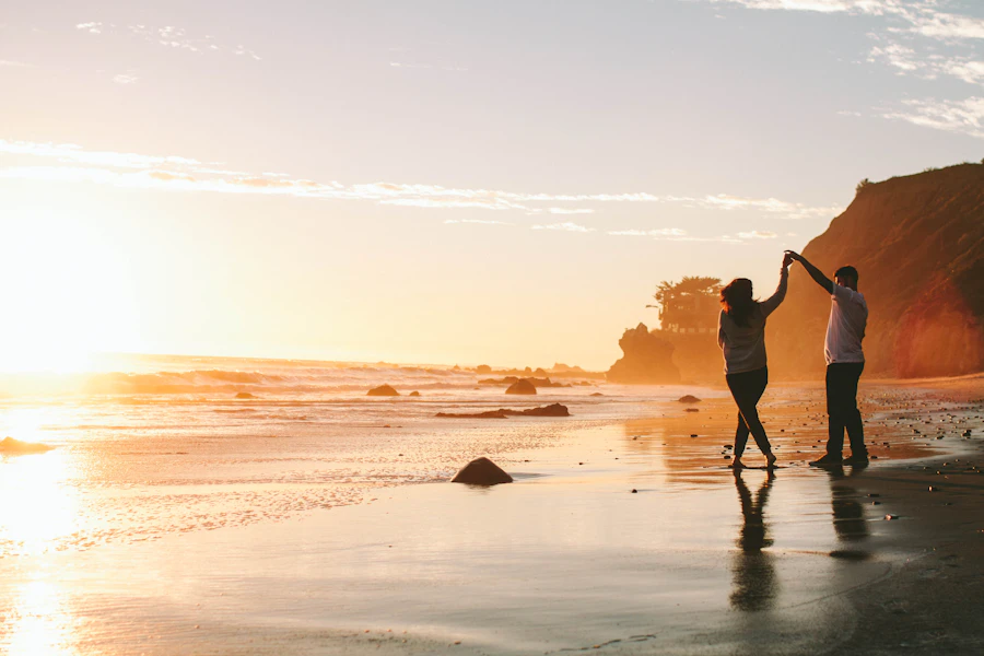 Casal de mãos dadas numa praia ao entardecer